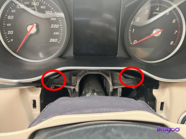Two lower instrument-cluster mounting screws marked for removal on a Mercedes W205